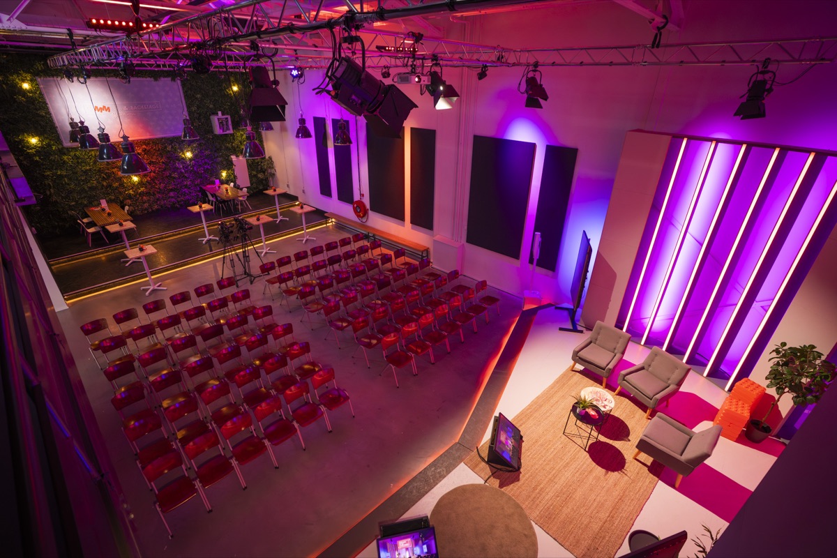 Overzicht van de studio met theateropstelling, loungehoek en warm studiolicht